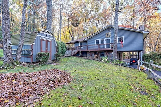 back of house with a wooden deck, a lawn, and a storage unit