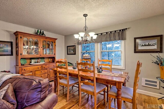 dining space with an inviting chandelier, hardwood / wood-style flooring, and a textured ceiling