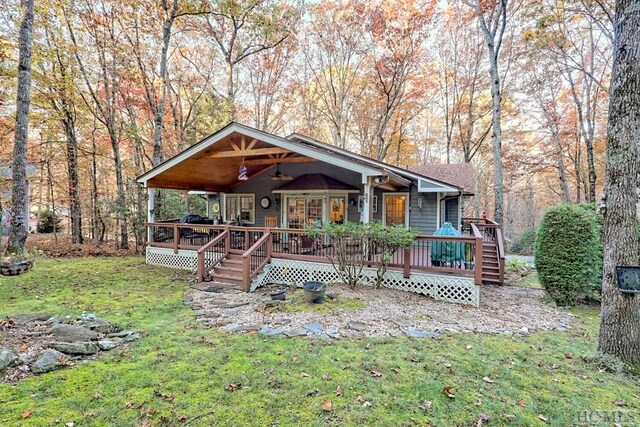 view of front of property featuring a wooden deck, ceiling fan, and a front lawn