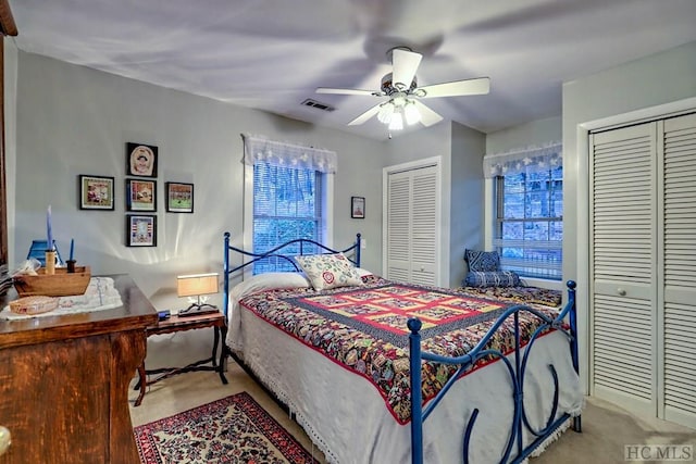 carpeted bedroom featuring ceiling fan and multiple closets