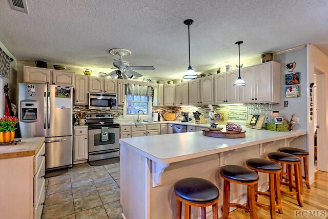 kitchen featuring sink, a kitchen breakfast bar, pendant lighting, ceiling fan, and stainless steel appliances