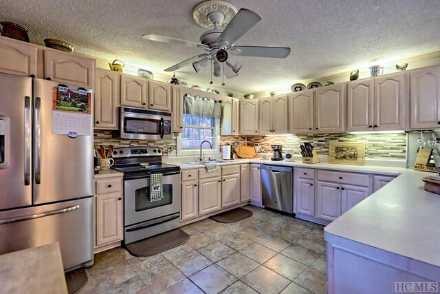 kitchen featuring sink, decorative backsplash, ceiling fan, stainless steel appliances, and a textured ceiling