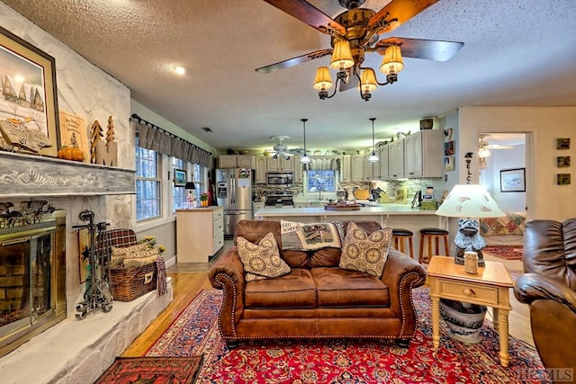 living room featuring ceiling fan, a fireplace, and a textured ceiling