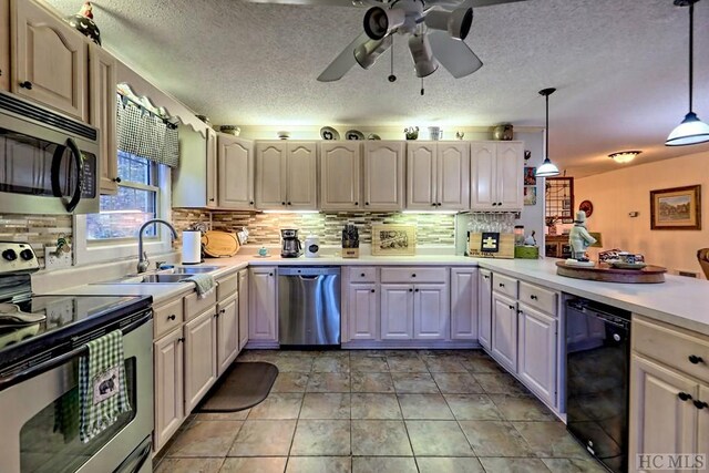 kitchen featuring appliances with stainless steel finishes, sink, backsplash, hanging light fixtures, and ceiling fan