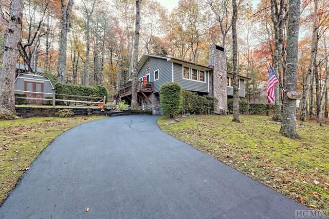 view of front of home with a wooden deck, a front yard, and a storage unit