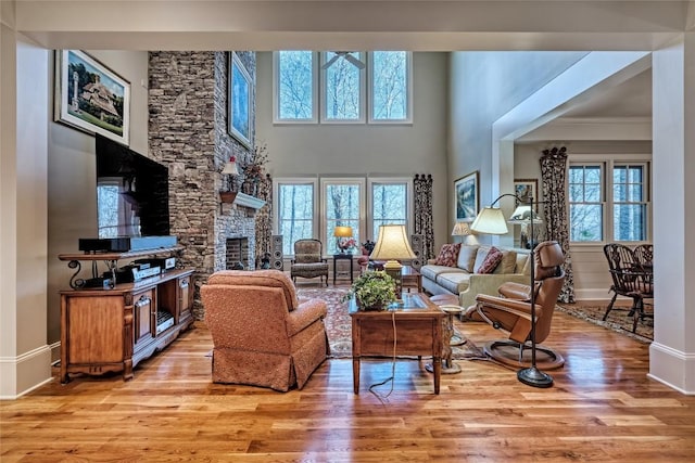 35 Creekwood Ct, Highlands, NC 28741 - living area with a stone fireplace, light wood-type flooring, baseboards, a ceiling fan, and crown molding