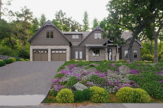 craftsman-style house featuring an attached garage, driveway, and stone siding