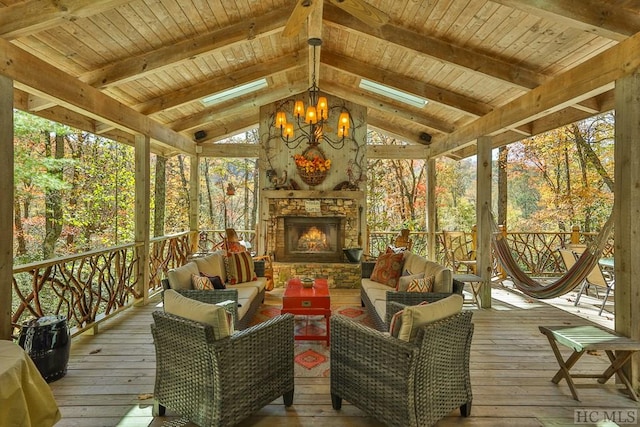 sunroom / solarium with lofted ceiling with beams, wooden ceiling, a chandelier, and an outdoor stone fireplace