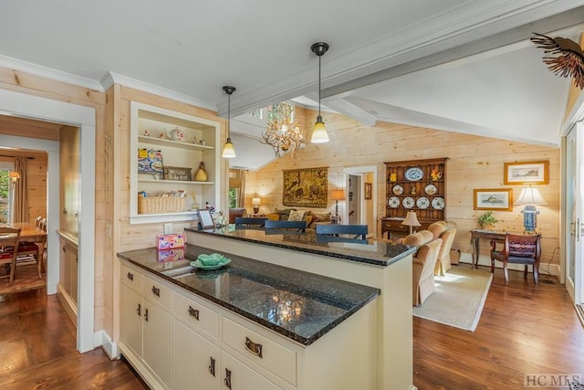 kitchen featuring lofted ceiling with beams, a peninsula, dark wood-type flooring, and dark stone counters