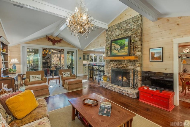 living area with a fireplace, lofted ceiling with beams, an inviting chandelier, wooden walls, and wood finished floors