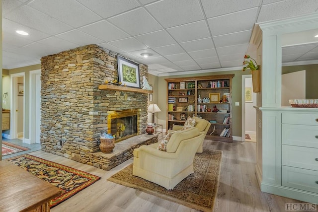 sitting room with baseboards, a fireplace, ornamental molding, and wood finished floors