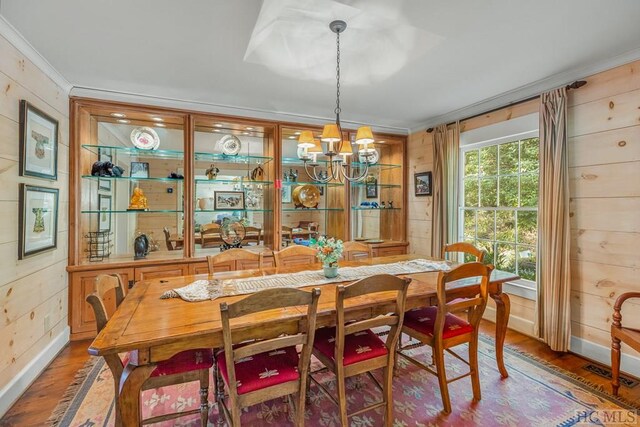 dining room featuring an inviting chandelier, wood finished floors, and wooden walls