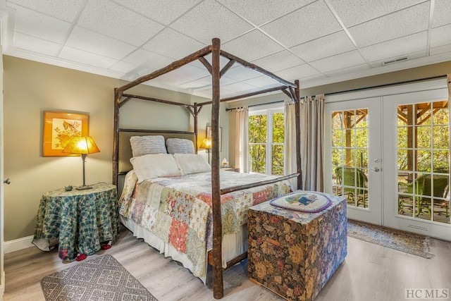 bedroom featuring access to outside, a drop ceiling, and wood finished floors