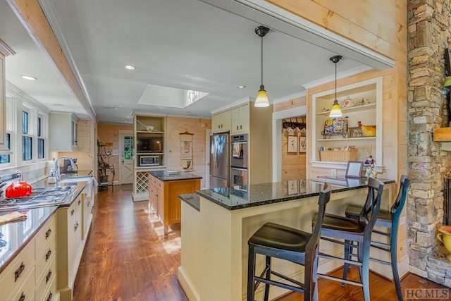 kitchen with dark stone counters, a kitchen breakfast bar, dark wood-type flooring, a center island, and stainless steel appliances