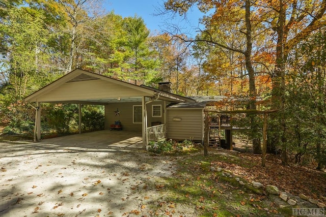 view of front of property featuring a chimney, a carport, and concrete driveway