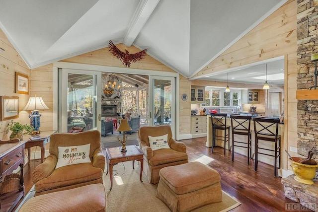 living area with lofted ceiling with beams, a stone fireplace, wood walls, and wood finished floors