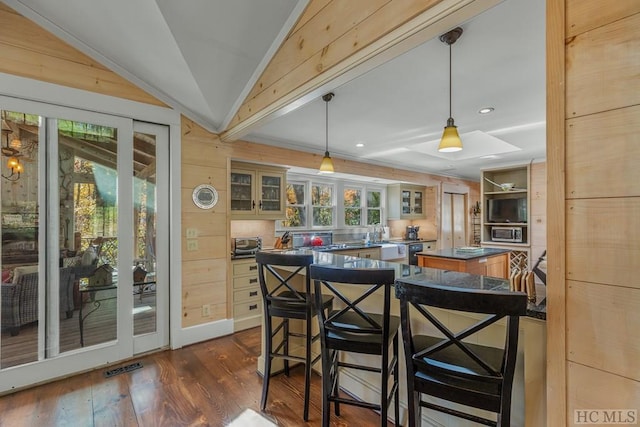 kitchen featuring dark wood-type flooring, a kitchen island, visible vents, vaulted ceiling, and glass insert cabinets