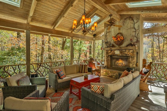 sunroom / solarium featuring lofted ceiling with beams, an inviting chandelier, plenty of natural light, and an outdoor stone fireplace