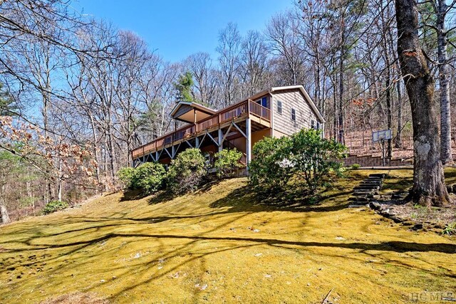 back of property featuring a wooden deck and a lawn