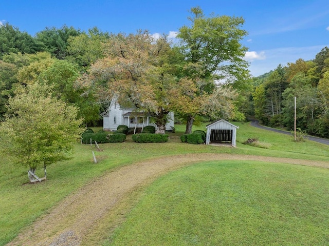 232 Dobson Rd, Franklin, NC 28734 - view of green lawn featuring a carport, driveway, an outbuilding, a wooded view, and an outdoor structure