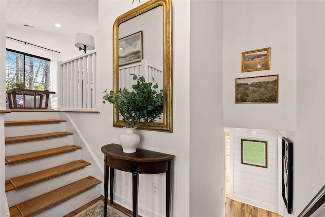 staircase with wood finished floors, baseboards, and recessed lighting