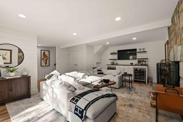 living room with beverage cooler, light wood finished floors, wooden walls, a dry bar, and recessed lighting