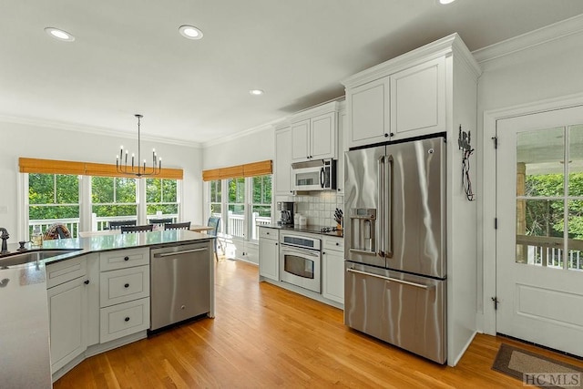 kitchen with white cabinetry, hanging light fixtures, a notable chandelier, stainless steel appliances, and backsplash