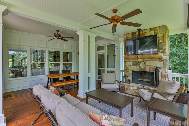 sunroom / solarium with beamed ceiling, ceiling fan, and a fireplace