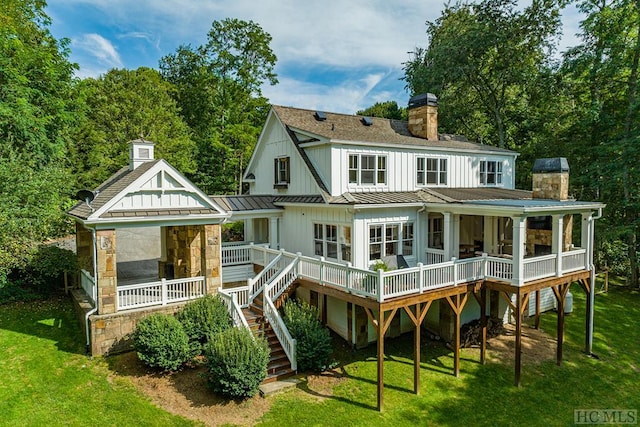 back of property featuring a yard, a sunroom, and a deck