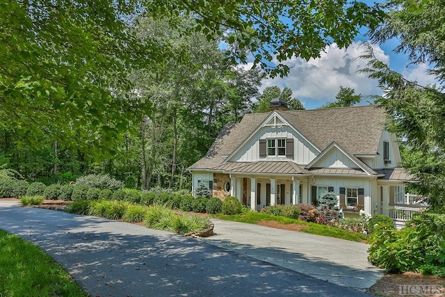 view of front of property featuring metal roof, roof with shingles, a chimney, and a standing seam roof