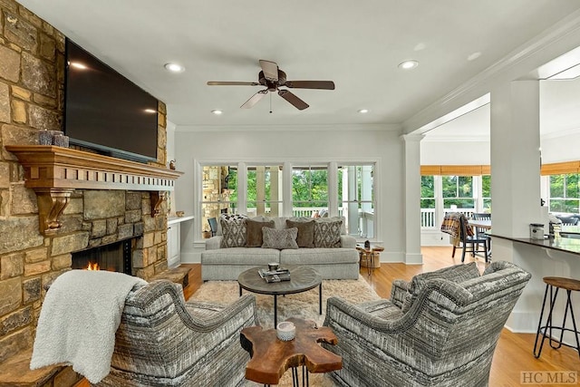 living room with ceiling fan, ornamental molding, a fireplace, and light hardwood / wood-style floors