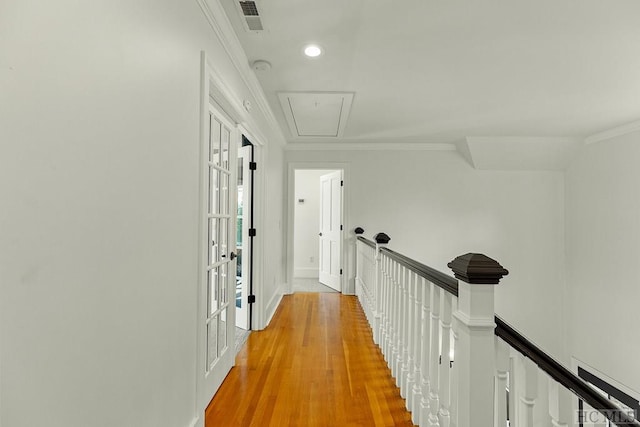 hall with french doors, ornamental molding, and light wood-type flooring