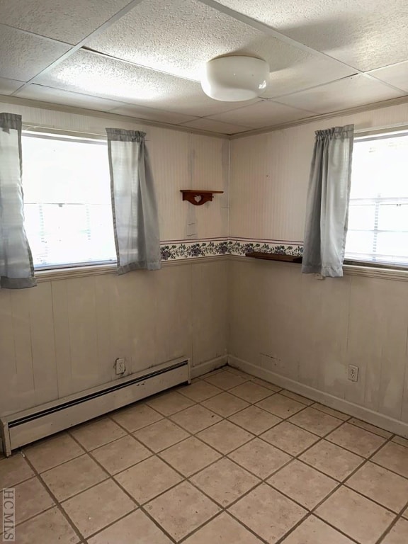 spare room featuring a healthy amount of sunlight, wood walls, and a baseboard radiator