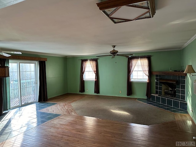 unfurnished living room with a tiled fireplace, ceiling fan, hardwood / wood-style flooring, and ornamental molding