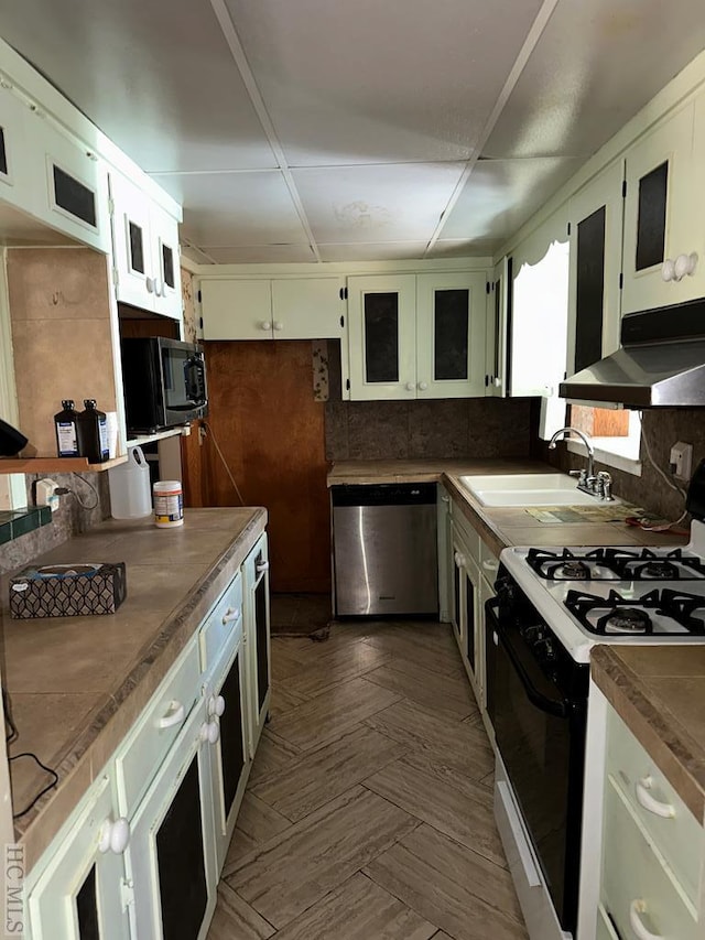 kitchen with sink, white cabinetry, stainless steel appliances, dark parquet floors, and decorative backsplash