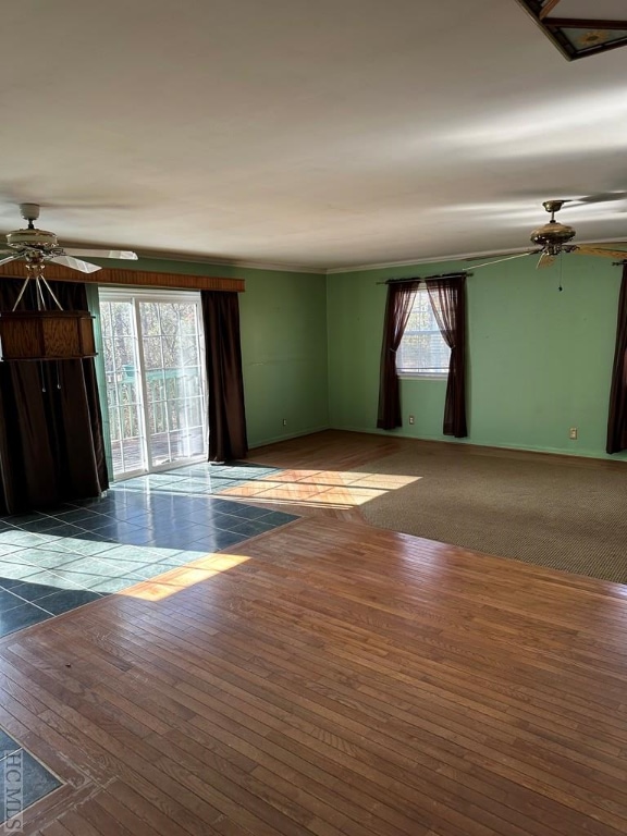 unfurnished living room featuring crown molding, ceiling fan, and dark hardwood / wood-style flooring