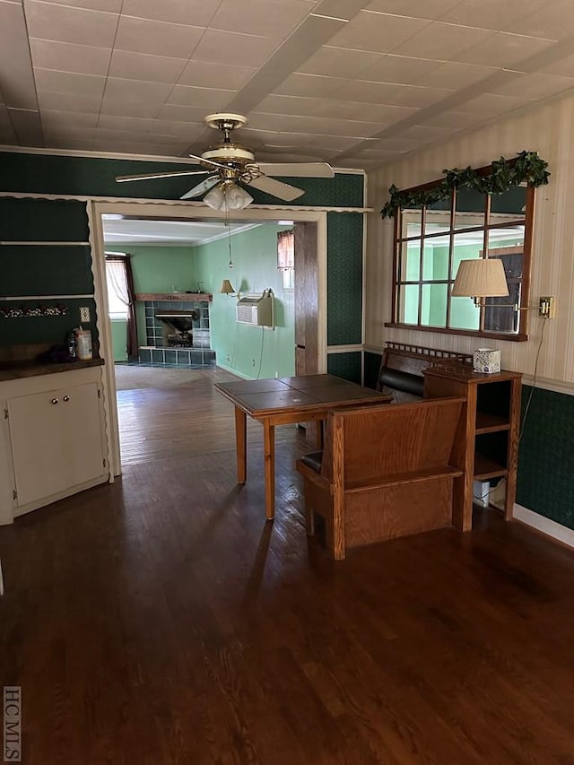 unfurnished dining area featuring ceiling fan, dark hardwood / wood-style floors, and a tile fireplace