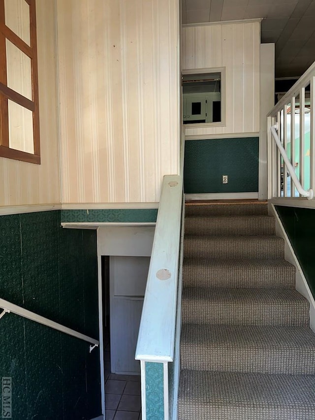 stairway with tile patterned floors and wood walls