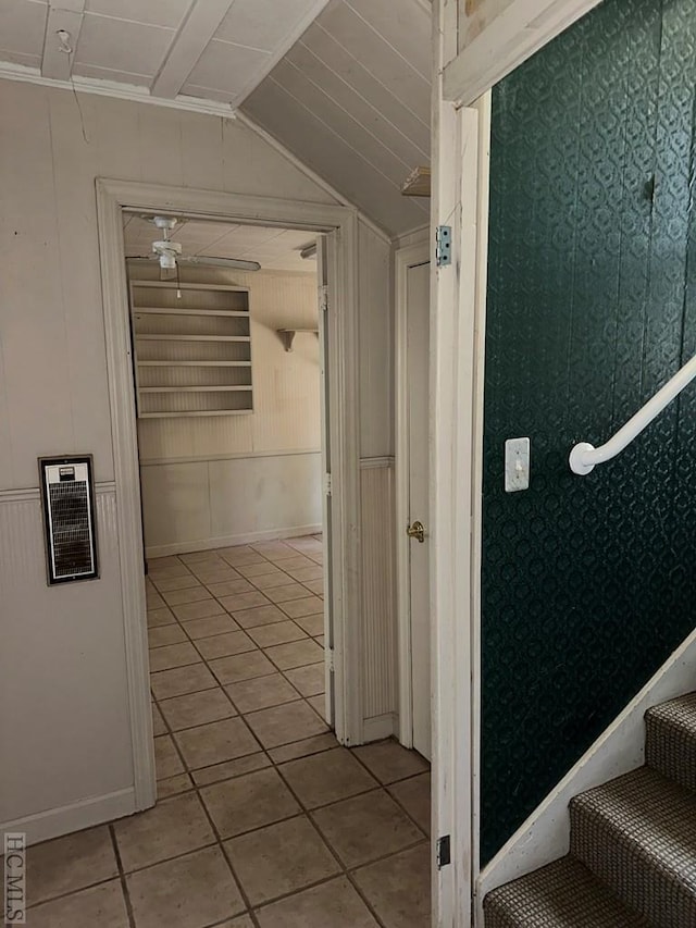 hallway featuring lofted ceiling, light tile patterned floors, and wooden walls