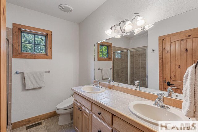 full bath with a stall shower, tile patterned flooring, baseboards, toilet, and double vanity