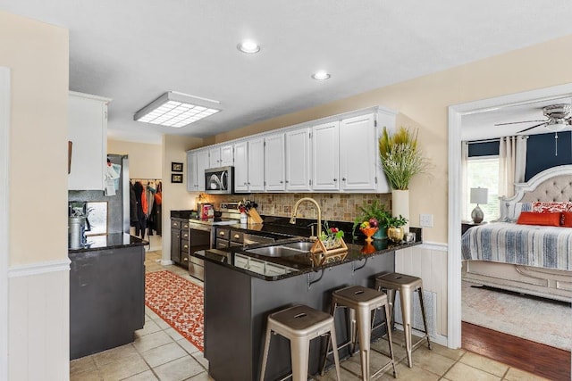 150 Lauren Ln, Franklin, NC 28734 - kitchen with appliances with stainless steel finishes, white cabinets, wainscoting, a peninsula, and a ceiling fan