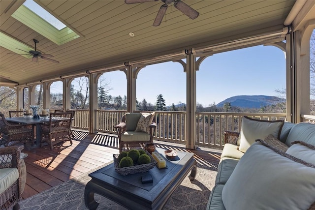 wooden deck featuring a mountain view, an outdoor hangout area, outdoor dining space, and a ceiling fan