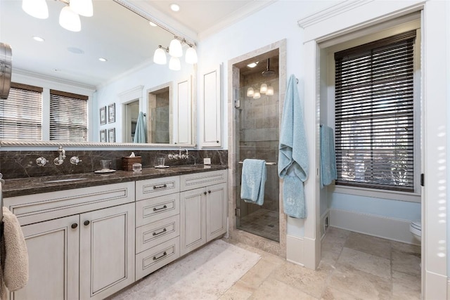 full bath with crown molding, double vanity, a shower stall, and a sink