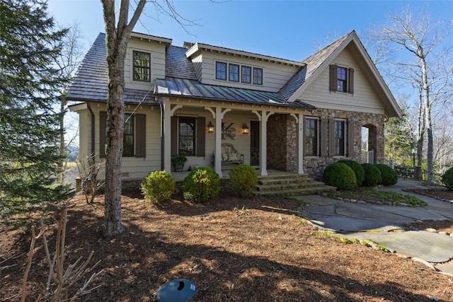 view of front of house featuring metal roof, stone siding, a porch, and a standing seam roof