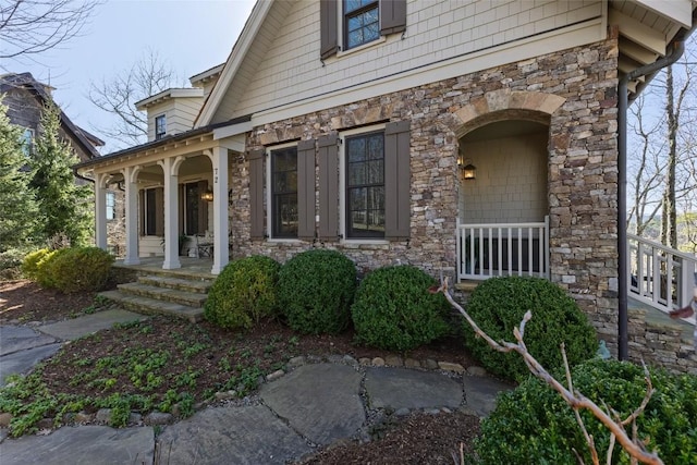 doorway to property featuring covered porch and stone siding