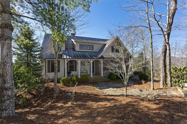 view of front of home featuring a chimney, covered porch, and metal roof