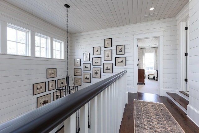 hallway with dark wood-type flooring, plenty of natural light, an upstairs landing, and wooden ceiling