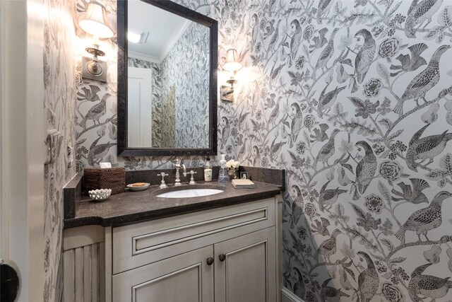 bathroom with vanity, crown molding, and wallpapered walls