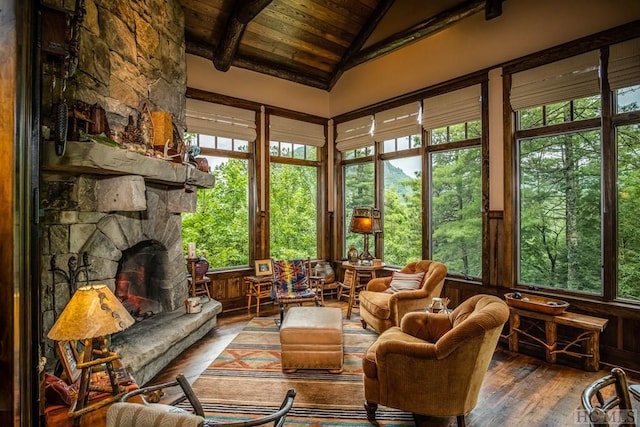 sunroom with vaulted ceiling with beams, wood ceiling, and a fireplace