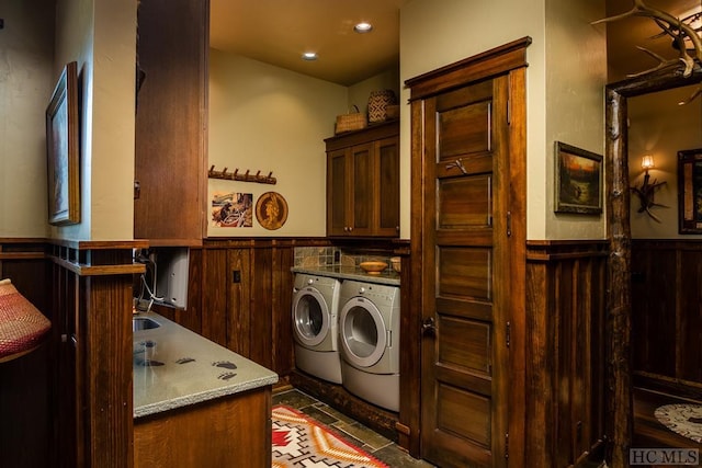 clothes washing area with cabinets, washer and clothes dryer, and wooden walls